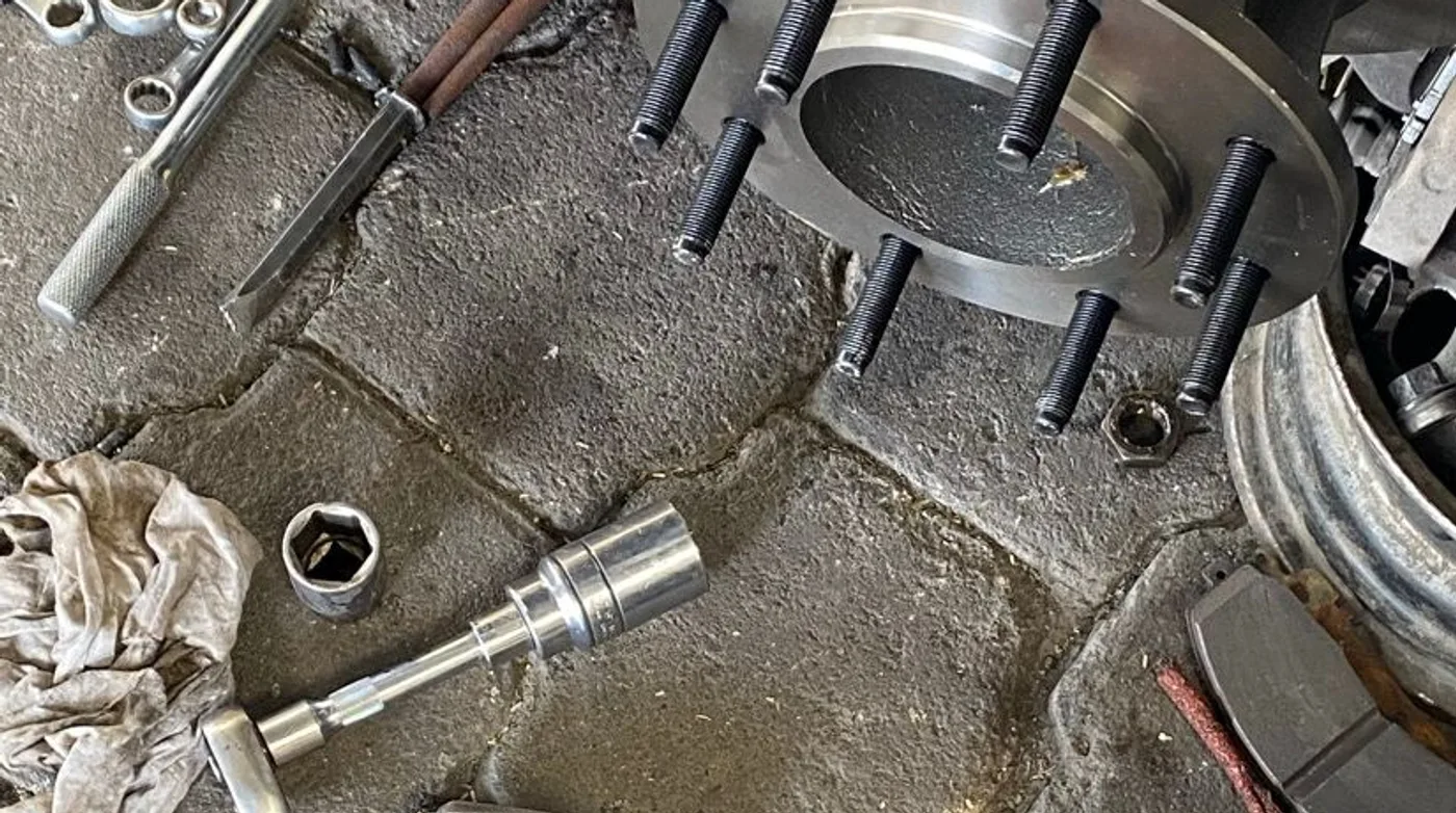 Piezas de freno desmontadas sobre el piso del taller durante una reparación